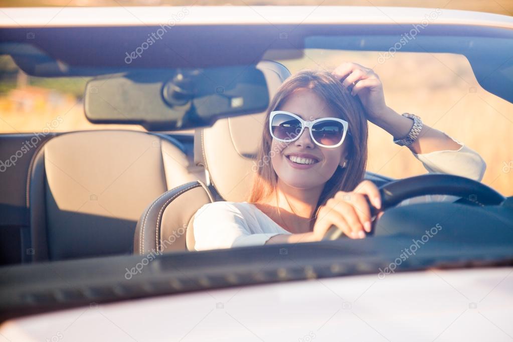 the girl sitting behind the wheel of a white convertible