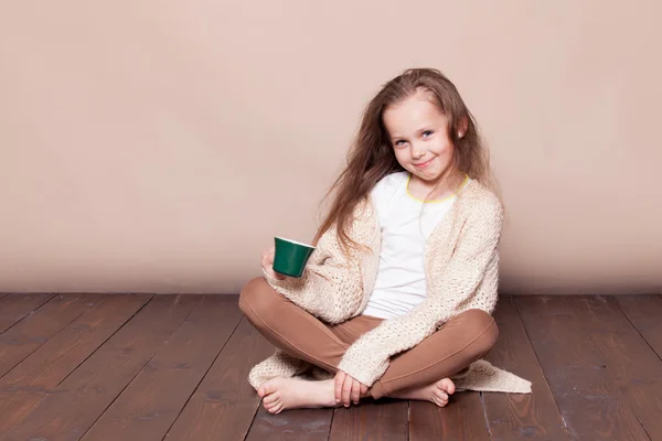 Bambina seduta sul pavimento e che beve tè — Foto Stock