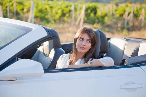 Chica conductor se sienta detrás del volante de un convertible blanco — Foto de Stock