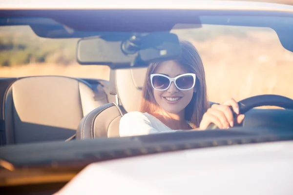 Chica conductor se sienta detrás del volante de un convertible blanco —  Fotos de Stock