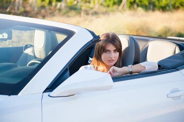 Девушка-водитель сидит в белом кабриолете — стоковое фото