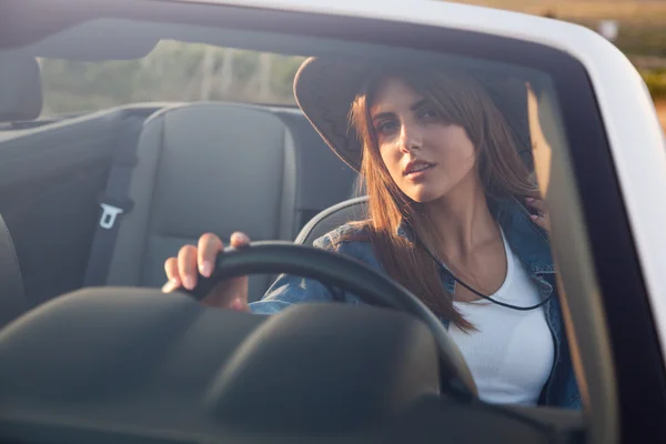 Cowboy girl driver sits in white cabriolet — Stock Photo, Image