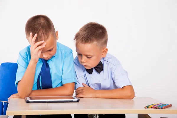 二人の少年は、デスクとタブレットで座っています。 — ストック写真