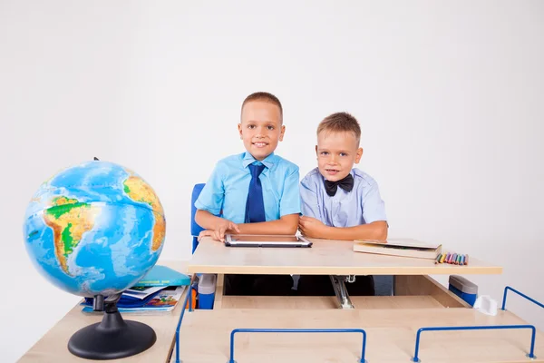 Twee jongens zitten aan een bureau en zoek Tablet — Stockfoto