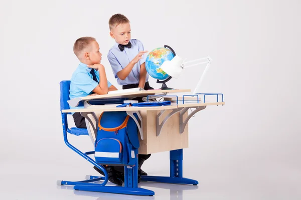 二人の少年は、学校での机のための世界を学んでいます。 — ストック写真