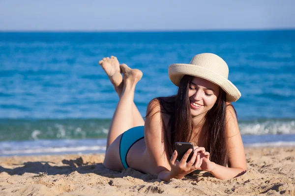 Mooi meisje liggen op een strand en de telefoon praten — Stockfoto