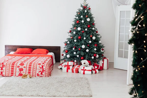 Nochevieja dormitorio interior con cama de decoración roja y árbol de Navidad con regalos — Foto de Stock