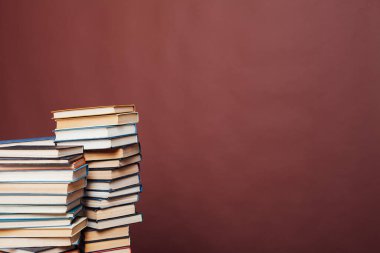 Üniversitenin kahverengi arka planı üzerine kütüphanede sınavlar için bir yığın eğitim kitabı