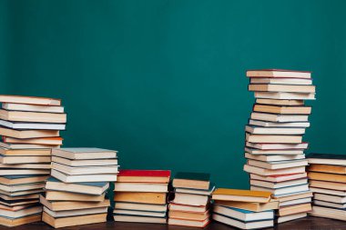 Üniversitenin yeşil arka planı üzerine kütüphanede sınavlar için bir yığın eğitim kitabı