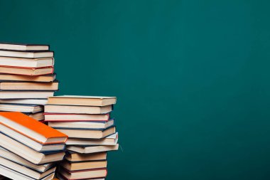 Üniversitenin yeşil arka planı üzerine kütüphanede sınavlar için bir yığın eğitim kitabı