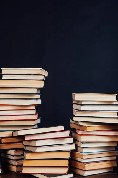 De nombreuses piles de livres éducatifs à étudier dans la bibliothèque sur un fond noir — Photo