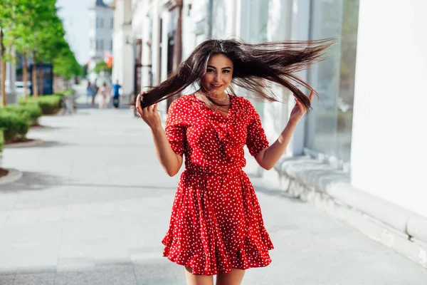 Kırmızı yazlık elbiseli güzel, şık esmer kadın sokakta yürüyor. — Stok fotoğraf