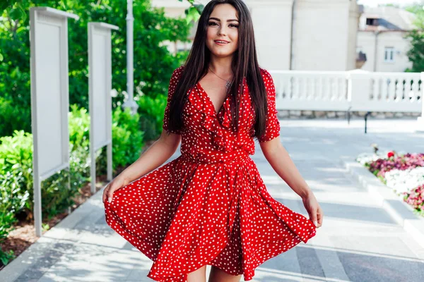 Kırmızı yazlık elbiseli güzel, şık esmer kadın sokakta yürüyor. — Stok fotoğraf
