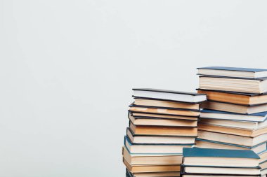 Kütüphanede beyaz bir arkaplan üzerine okumak ve eğitim için kitap yığınları