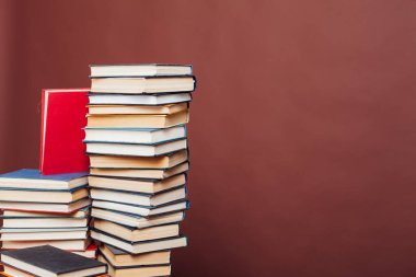 Kütüphanedeki kahverengi arkaplan üzerine okumak ve eğitim için kitap yığınları
