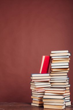 Kütüphanedeki kahverengi arkaplan üzerine okumak ve eğitim için kitap yığınları