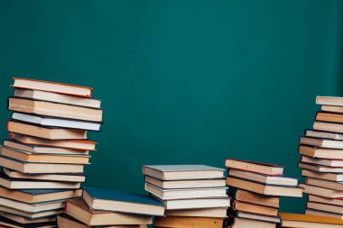 Üniversite kütüphanesinde yeşil bir arkaplan üzerine okumak ve eğitim için kitap yığınları