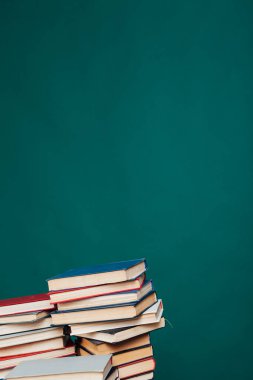 Üniversite kütüphanesinde yeşil bir arkaplan üzerine okumak ve eğitim için kitap yığınları