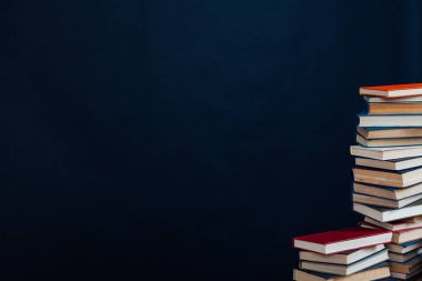 Üniversite kütüphanesinde siyah bir arkaplan üzerine okumak ve eğitim için kitap yığınları