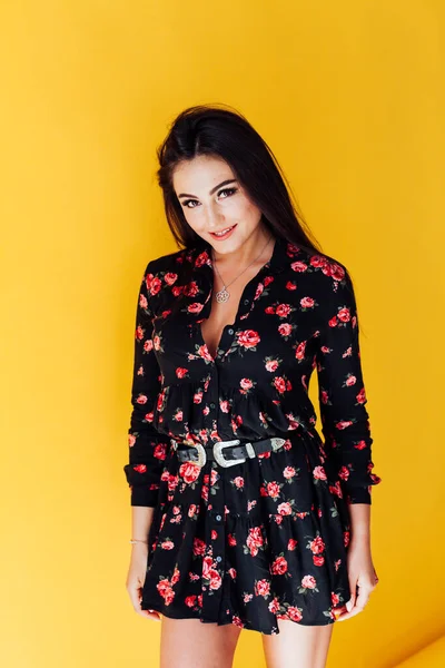 Mooie modieuze brunette vrouw in een jurk met bloemen — Stockfoto