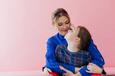 Anne-kız kucaklaşır. Aile pembe arka planı.