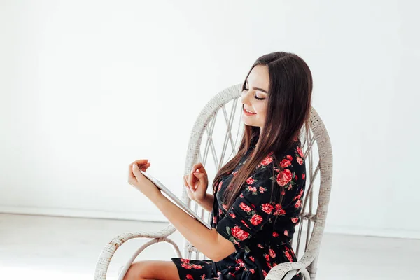 Όμορφη μοντέρνα μελαχρινή γυναίκα σε ένα φόρεμα εξετάζει το tablet στο διαδίκτυο — Φωτογραφία Αρχείου
