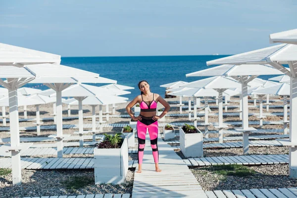 Piękna kobieta zajmująca się gimnastyką fitness na plaży nad morzem — Zdjęcie stockowe