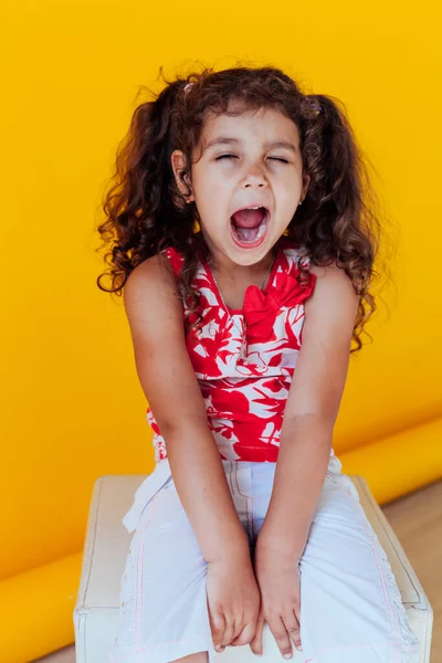 Beautiful little curly girl with braids yawns