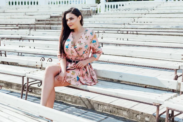 Schöne modische brünette Frau in einem Kleid mit Blumen spaziert im Park — Stockfoto