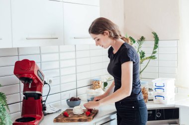 Güzel kadın pasta şefi mutfakta tatlı kekler yapıyor.