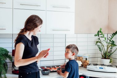 Anne pasta şefi ve oğlu mutfakta tatlı kekler pişiriyor.