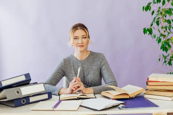 stock image woman in business suit at work in office at a table with books and documents