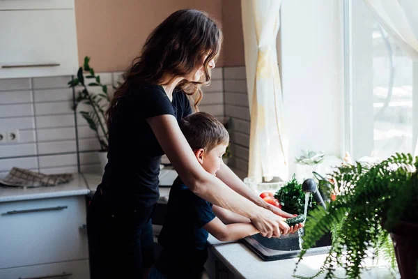 beautiful mom and son wash fresh vegetables