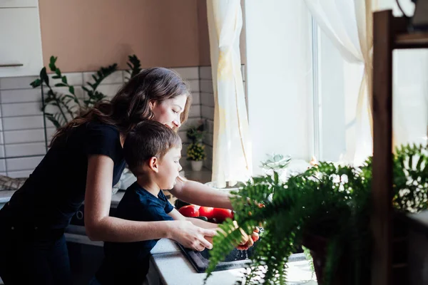 beautiful mom and son wash fresh vegetables