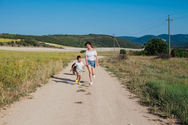 Maman et son fils marchent le long d'une route rurale dans un champ — Photo