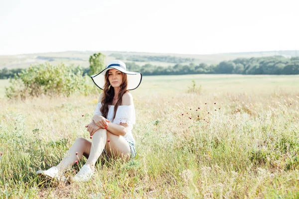 Retrato de uma mulher bonita em um chapéu com campos na natureza em um campo — Fotografia de Stock