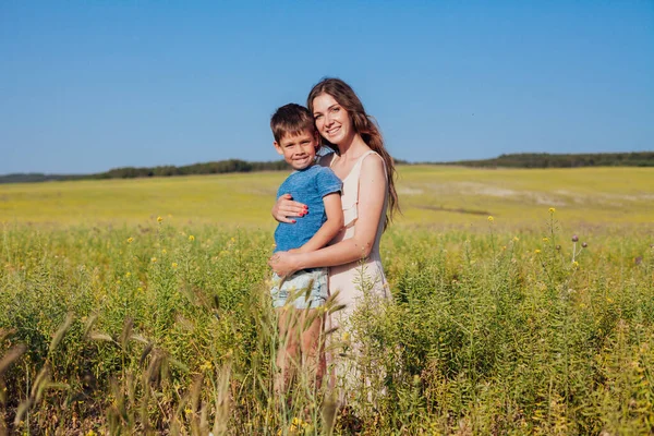 Madre e hijo juntos en un campo con flores amarillas — Foto de Stock