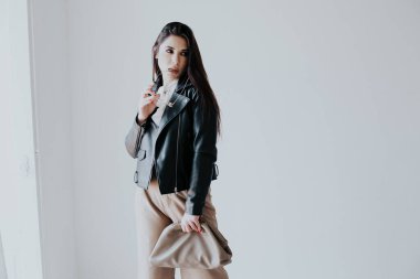 Siyah deri ceketli, şık, doğulu esmer bir kadının portresi.