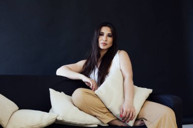 Kanepede ev kıyafetleri içinde güzel bir esmer kadının portresi.