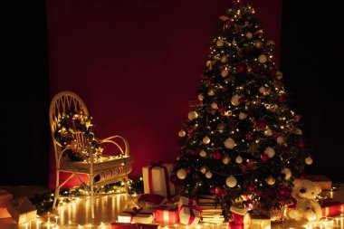 Noel ağacı, gece odasının içinde kırmızı bir zemin olarak yeni yıl için çelenk ışıkları hediye ediyor.