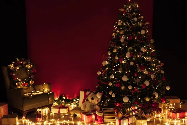 Árvore de Natal com presentes de luzes guirlanda para o ano novo no interior da sala de noite como um fundo vermelho — Fotografia de Stock
