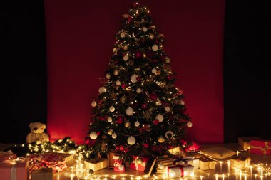 Noel ağacı, gece odasının içinde kırmızı bir zemin olarak yeni yıl için çelenk ışıkları hediye ediyor.