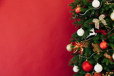 Noel ağacı, odanın içinde kırmızı bir zemin olarak yeni yıl için çelenk ışıkları hediye ediyor.