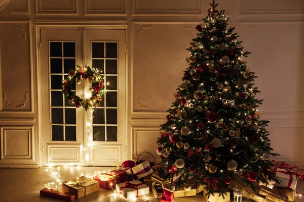 背景として、夜の室内で新年のためのガーランドライトの贈り物とクリスマスツリー — ストック写真