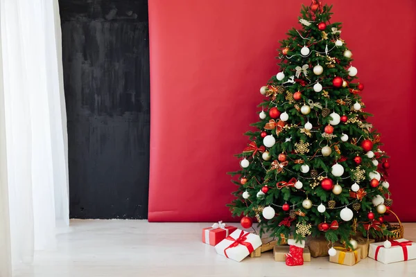 Árbol de Navidad con regalos de luces de guirnalda para el nuevo año en el interior de la habitación como fondo rojo — Foto de Stock