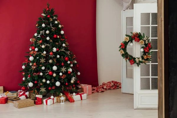 Kerstboom met geschenken van slinger lichten voor het nieuwe jaar in het interieur van de kamer als een rode achtergrond — Stockfoto