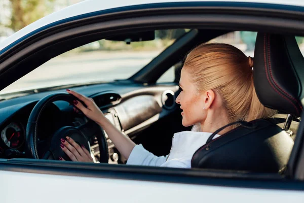 Piękna blond kierowca za kierownicą samochodu na drodze — Zdjęcie stockowe