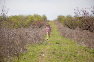 Pembe elbiseli güzel sarışın kadın çiçek bahçesinde yürüyor.