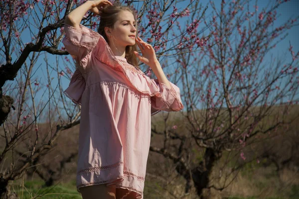 Pembe elbiseli güzel sarışın kadın çiçek bahçesinde yürüyor. — Stok fotoğraf