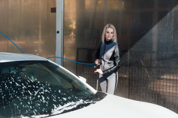 Piękna blondynka myje samochód w myjni samochodowej — Zdjęcie stockowe